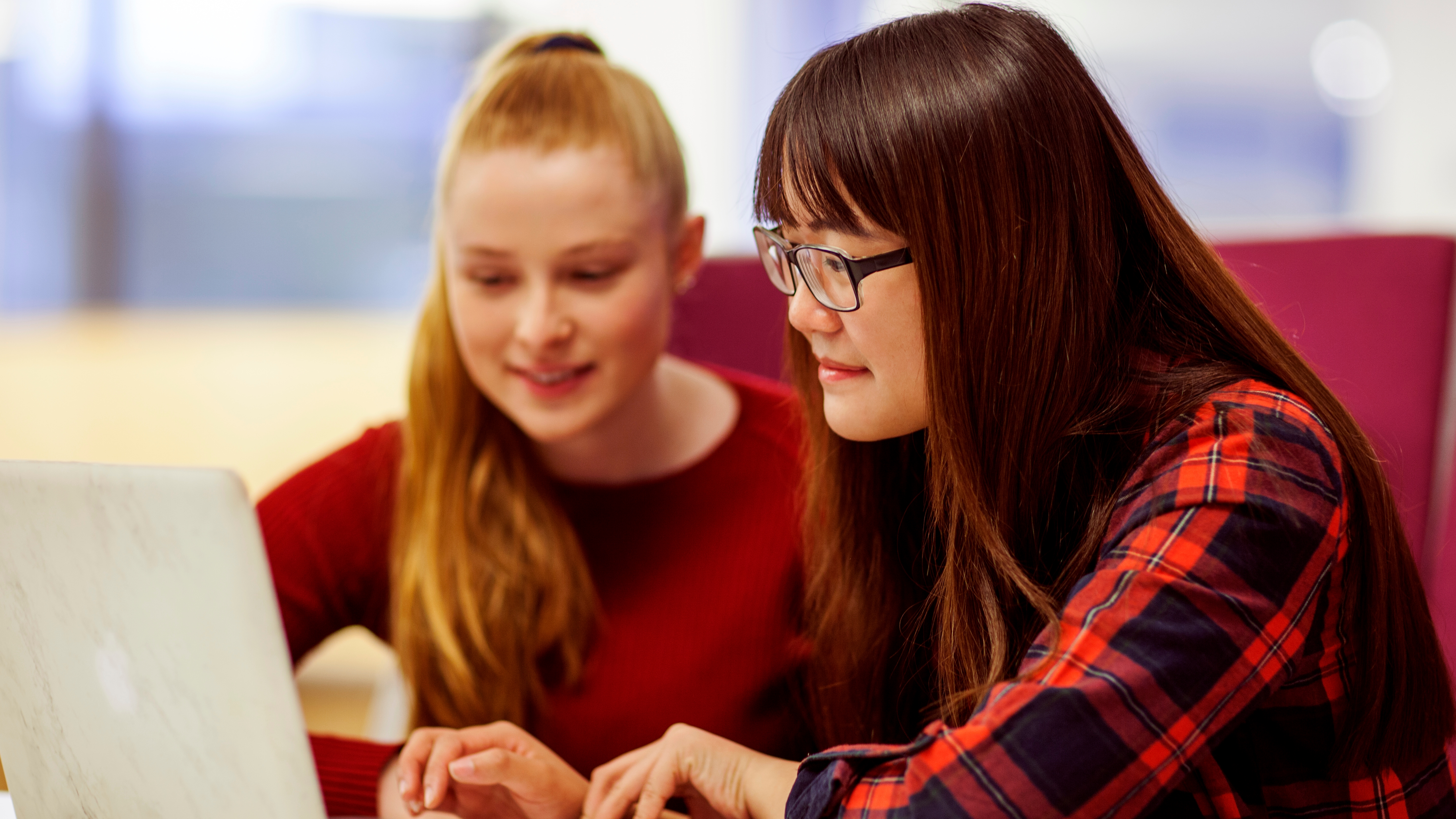 Two female students sitting facing a laptop