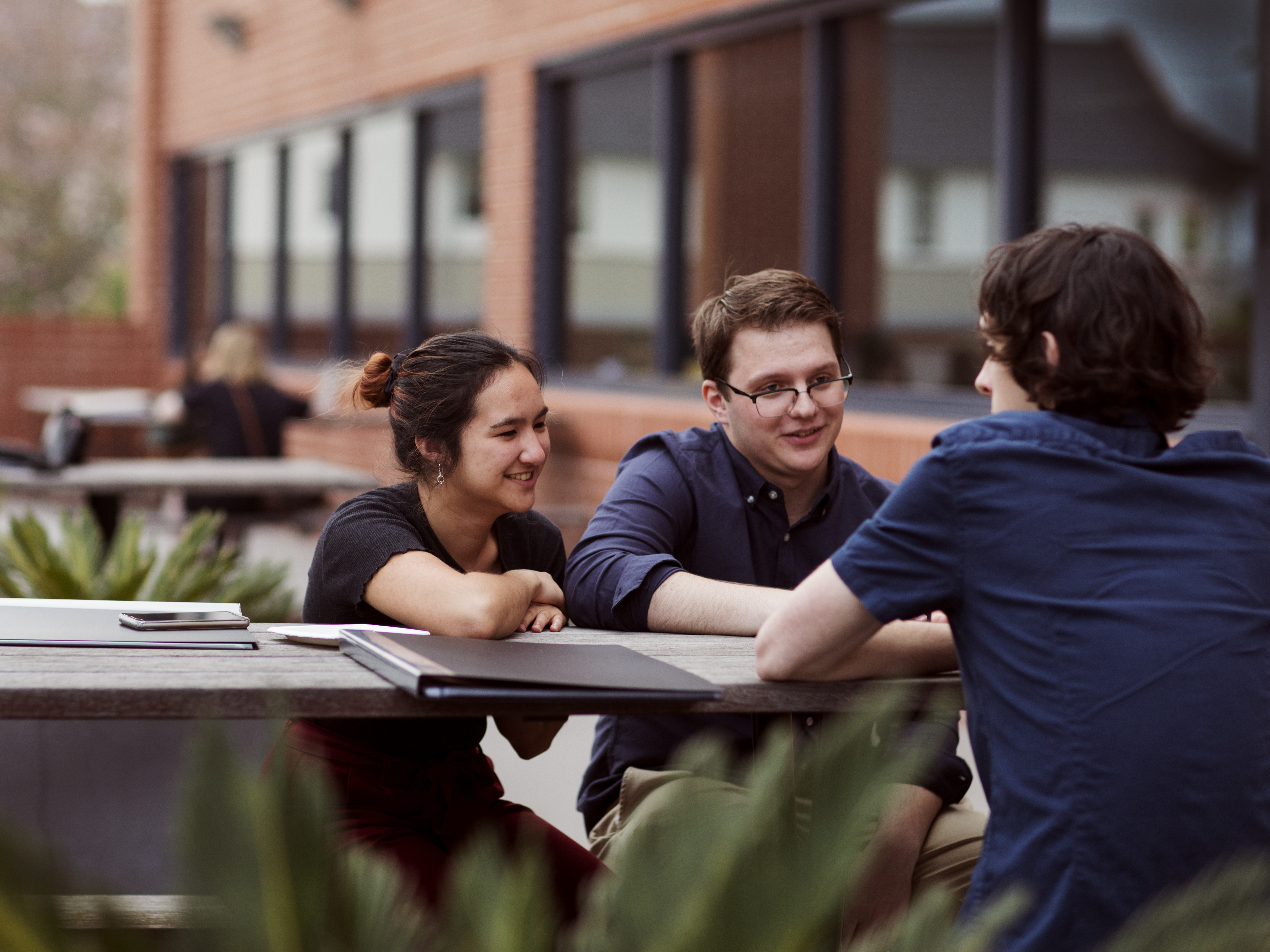 Group of three students sitting outdoors at a table