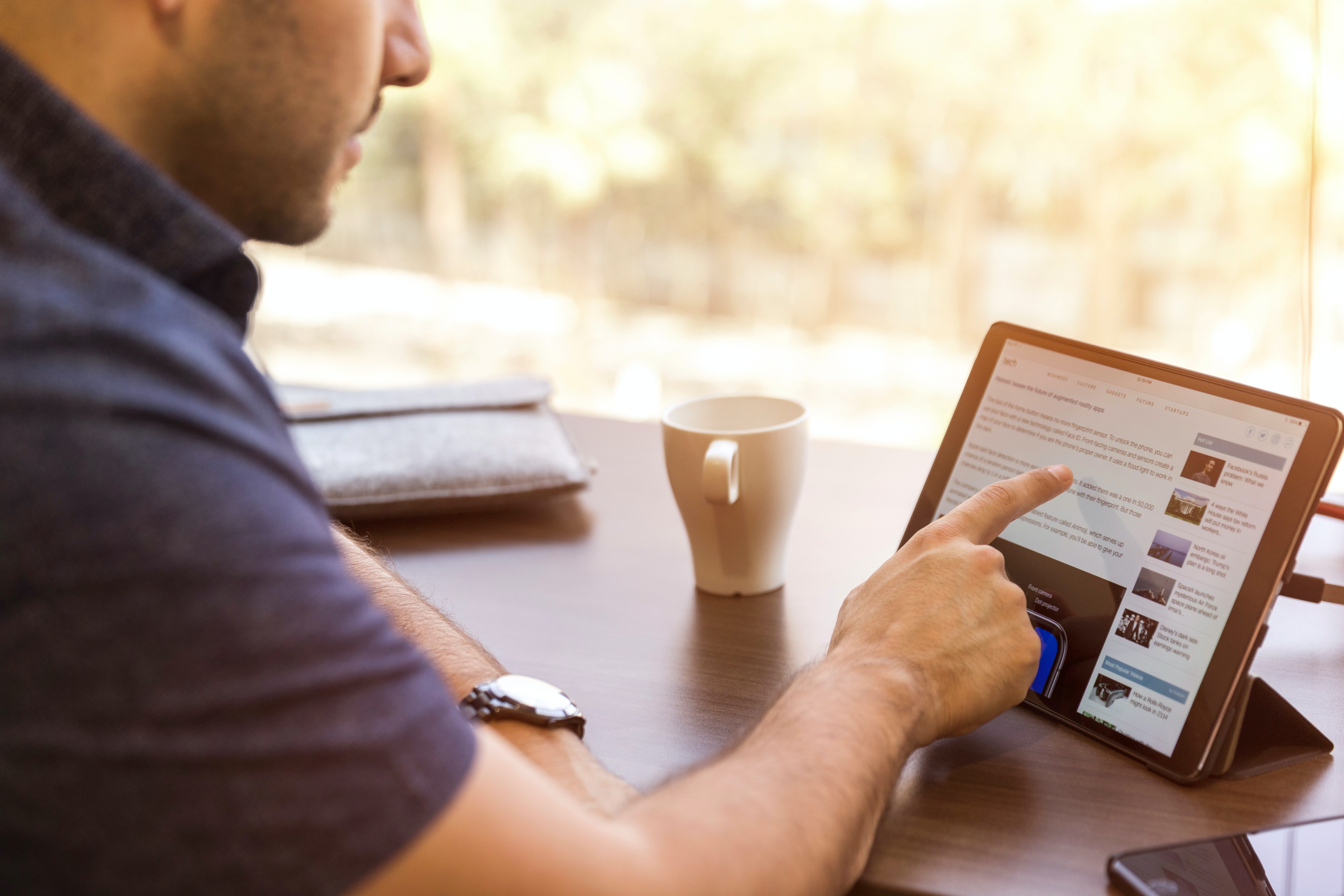 A man using his finger to tap an iPad