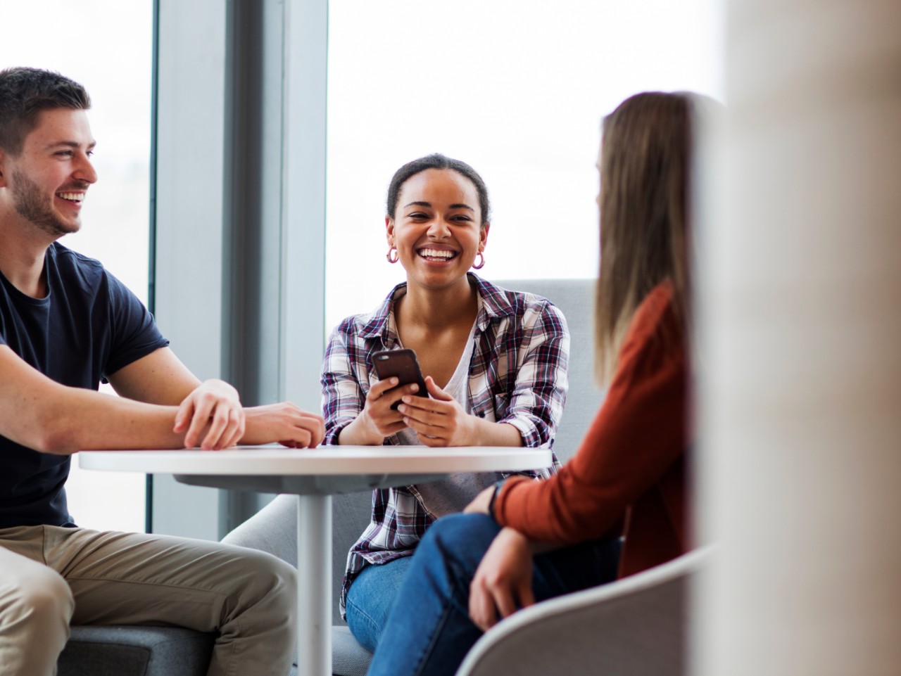 Group of 3 students sitting at a table on campus