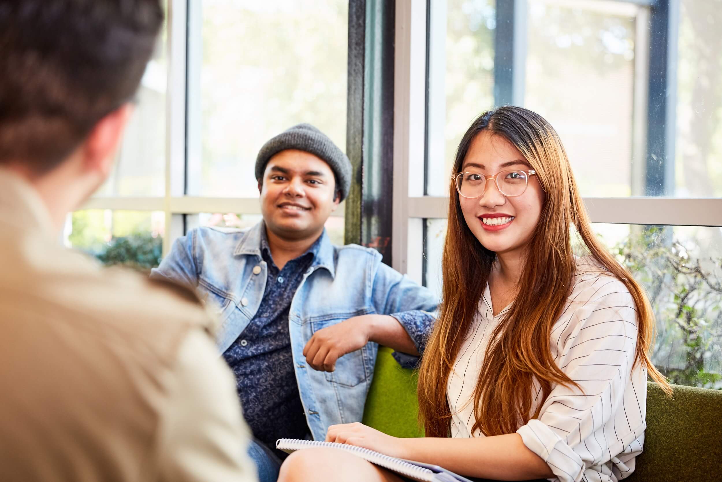 Group of three students sitting together in a common area on campus